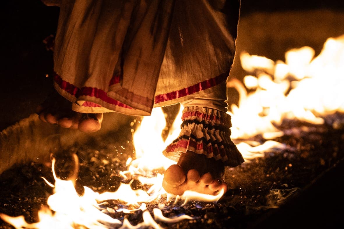 Dancer's feet walking barefoot across burning coals during a fire-walking ritual