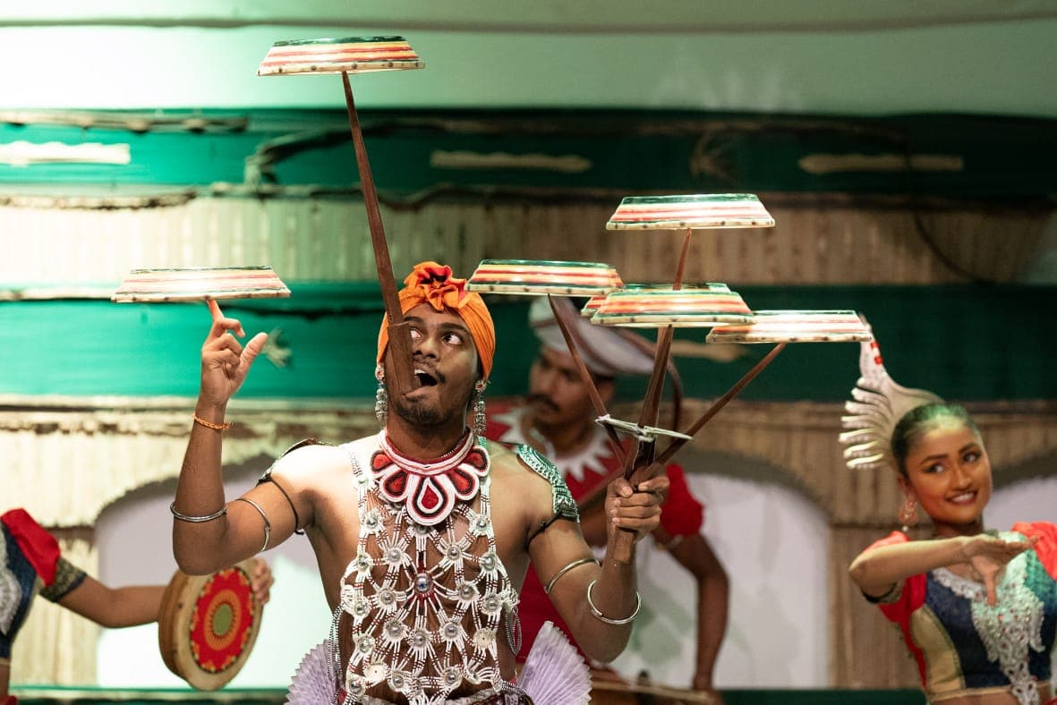 Dancer balancing traditional trays on sticks during a cultural performance