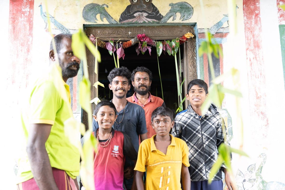 Three generations of a family gathered in the doorway of a painted village temple