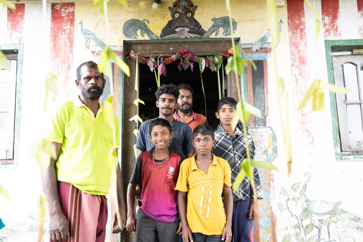 A father and five boys standing proudly outside their family home